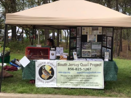 A picture of the SJQP table with a banner with the logo on it and a presentation board